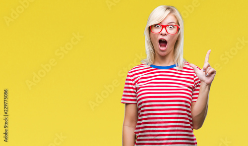 Young beautiful blonde woman wearing glasses over isolated background pointing finger up with successful idea. Exited and happy. Number one.