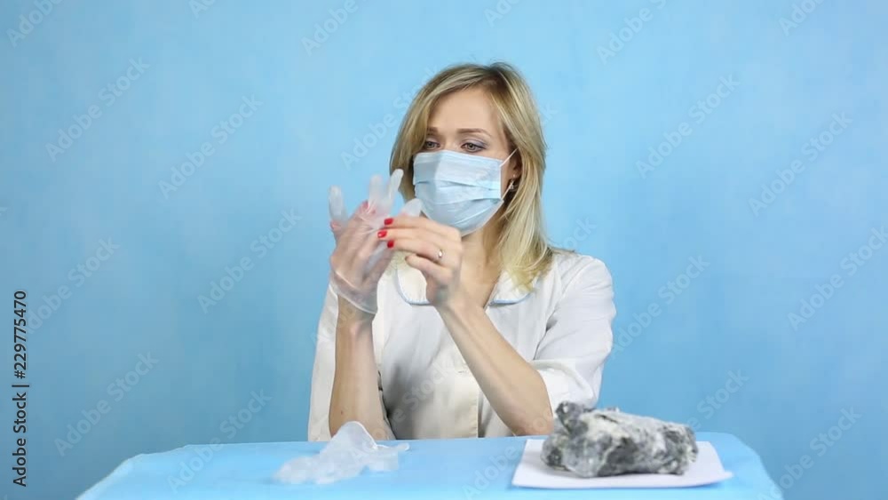 Girl lab technician puts gloves on his hands. A woman lab worker puts on her hands rubber protective gloves. Girl lab technician puts gloves on his hands. A woman lab worker puts on her hands rubber protective gloves.