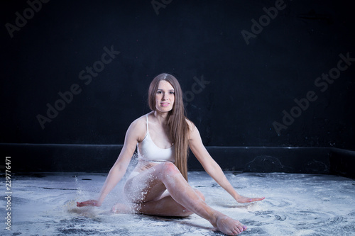Fototapeta Naklejka Na Ścianę i Meble -  sporty young girl throws flour on black background