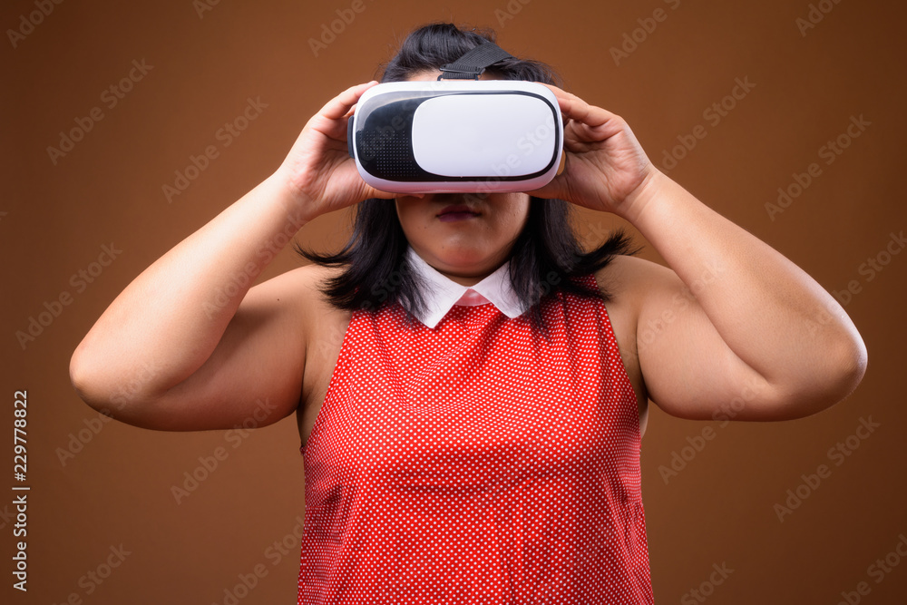 Beautiful overweight Asian woman using virtual reality VR glasses Beautiful overweight Asian woman using virtual reality VR glasses