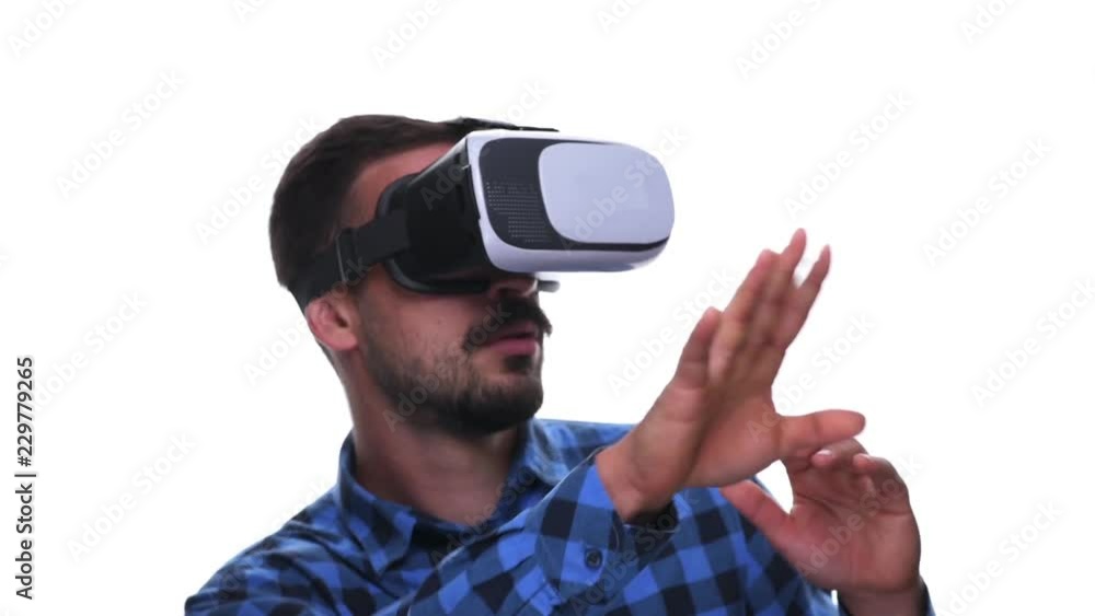 Shocked astonished man using virtual reality headset gesturing and avoiding simulated objects isolated on white background. Shocked astonished man using virtual reality headset gesturing and avoiding simulated objects isolated on white background.