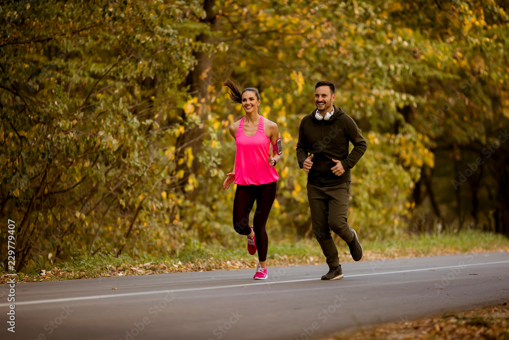 Fototapeta premium Young couple jogging together in park