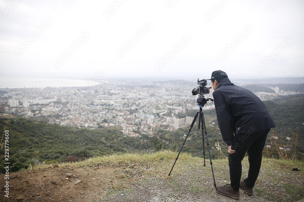 Photographer take a photo of city landscape on a hill