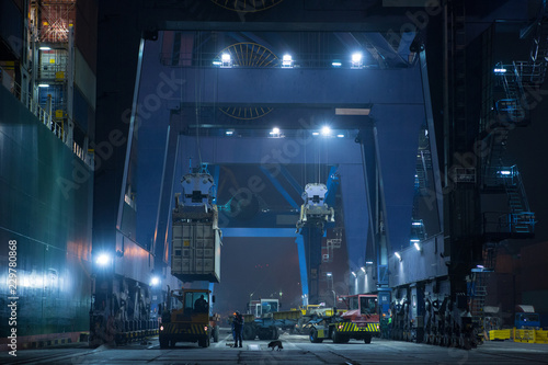 Large mooring crane unloads container ship at night. Container terminal crane will load container onto vessel. Industrial Container yard for Logistic Import Export business