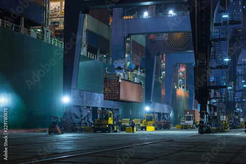 Large mooring crane unloads container ship at night. Container terminal crane will load container onto vessel. Industrial Container yard for Logistic Import Export business