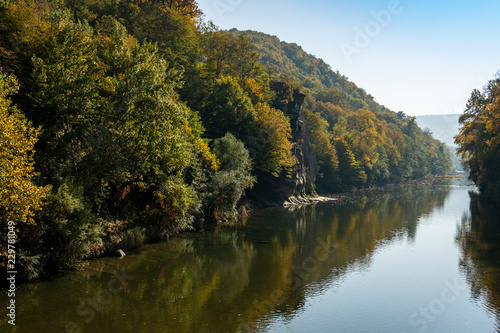 The autumn landscape with the “Cockerel” rock is reflected in the mountain river Psekups. Sunny day in the resort area of Goryachiy Klyuch. Krasnodar region. Excellent natural background for any idea.