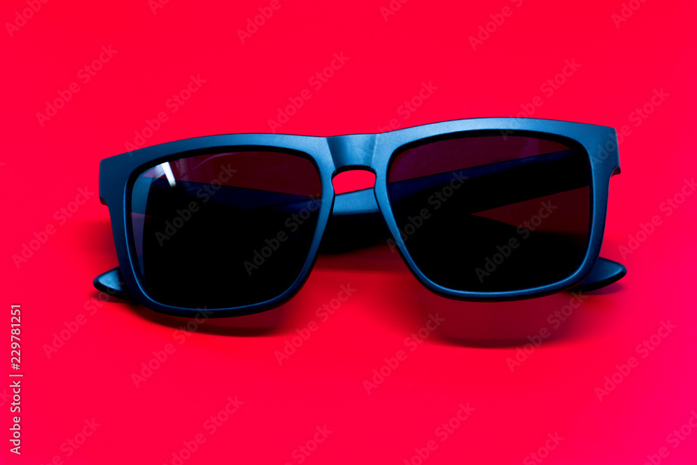 Fashion sunglasses isolated on red background, black plastic. Fashion sunglasses isolated on red background, black plastic.