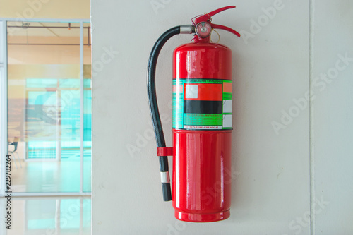 Fire extinguisher on the white cement wall background.
