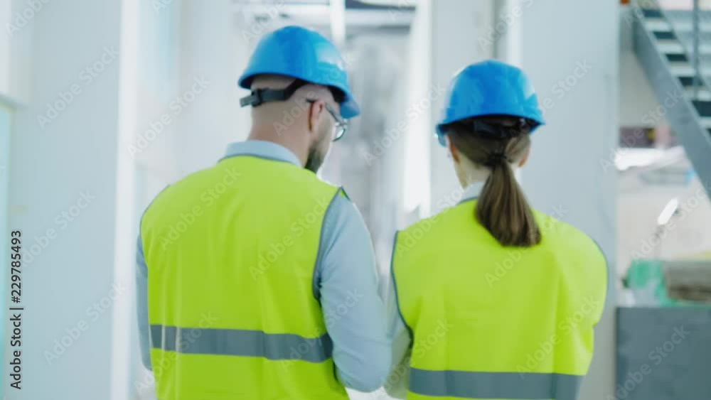 Engineers in hardhats have conversation in a factory Engineers in hardhats have conversation in a factory