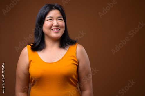 Portrait of beautiful overweight Asian woman smiling and thinking
