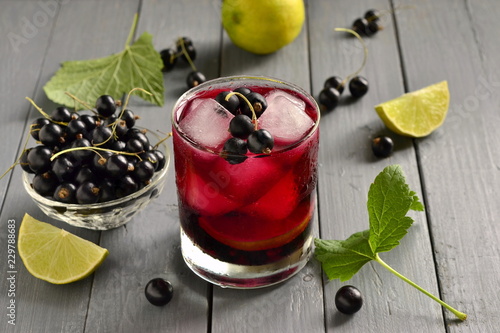 Cold lemonade with black currant, lime and ice cubes