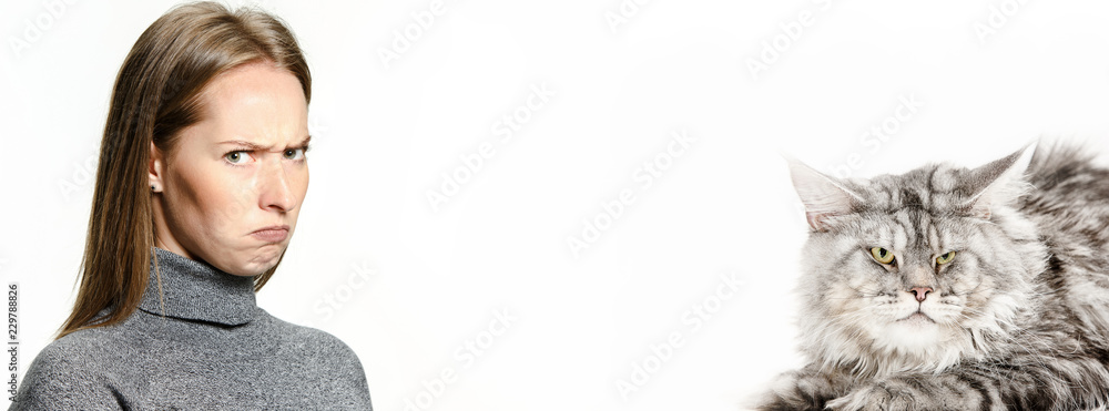 The angry and indignant woman and her cat over white background. The concept of humans and animals same emotions The angry and indignant woman and her cat over white background. The concept of humans and animals same emotions