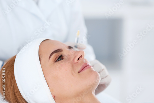 Woman undergoing face biorevitalization procedure in salon, closeup. Cosmetic treatment