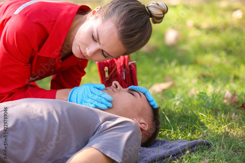 Photography Woman in uniform checking for breathing of unconscious man outdoors