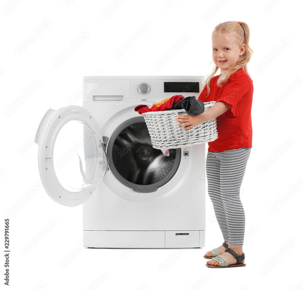 Cute little girl holding basket with laundry near washing machine on white background Cute little girl holding basket with laundry near washing machine on white background