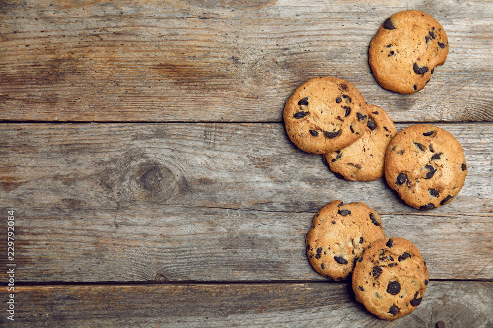Delicious chocolate chip cookies on wooden table, flat lay. Space for text