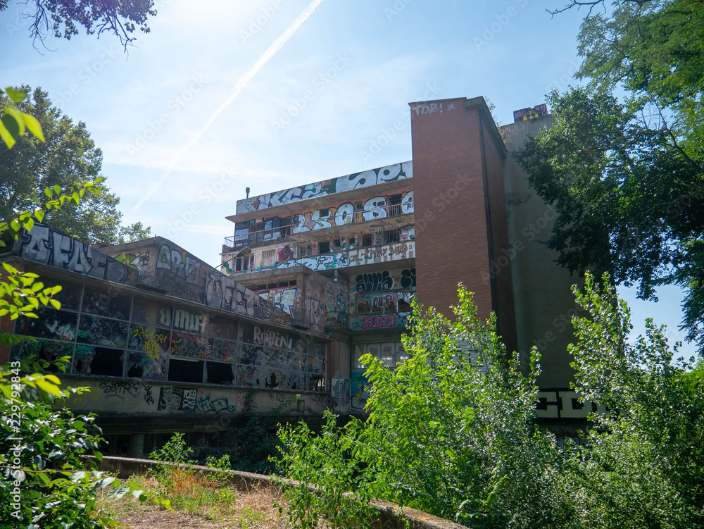 Exterior of an old abandoned building or factory, completely destroyed and vandalized, painted with colourful graffiti street art Exterior of an old abandoned building or factory, completely destroyed and vandalized, painted with colourful graffiti street art