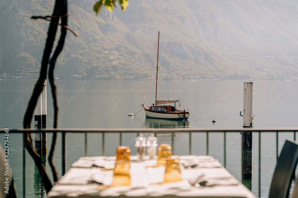 Mesa con platos con vistas de un lago con un barco