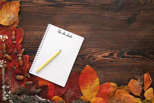 autumn leaves, cookies and paper notebook on wooden background