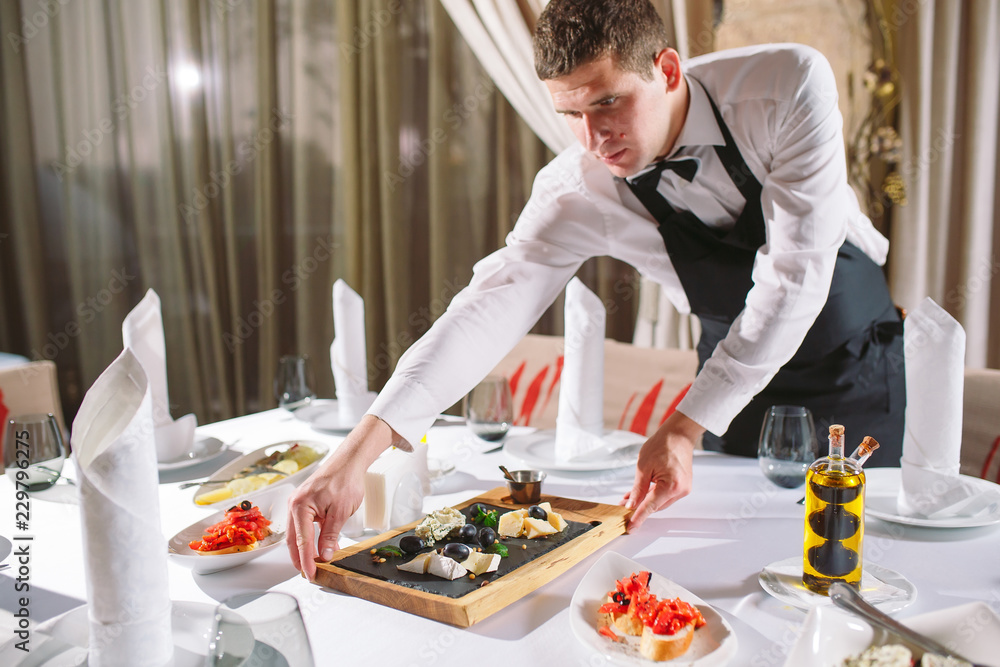 Fototapeta premium Waiter serving table in the restaurant preparing to receive guests.