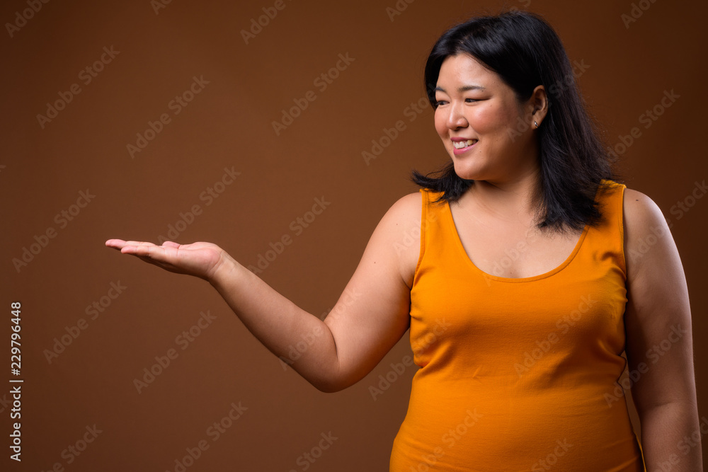 Smiling overweight Asian woman showing copy space Smiling overweight Asian woman showing copy space