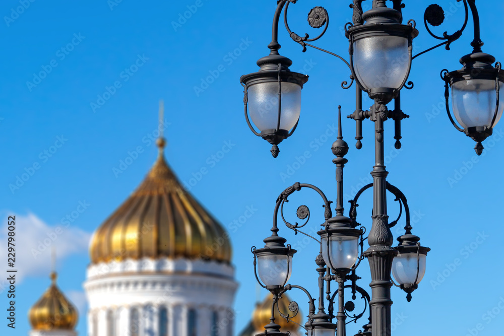 Cast iron street lamps on the Patriarch's Bridge against the blue sky and golden domes