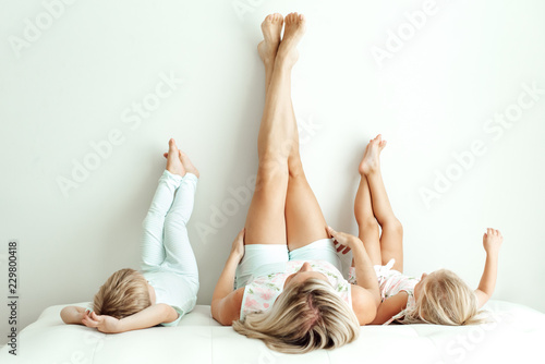 Mother and children lying on a bed with their feet on the wall