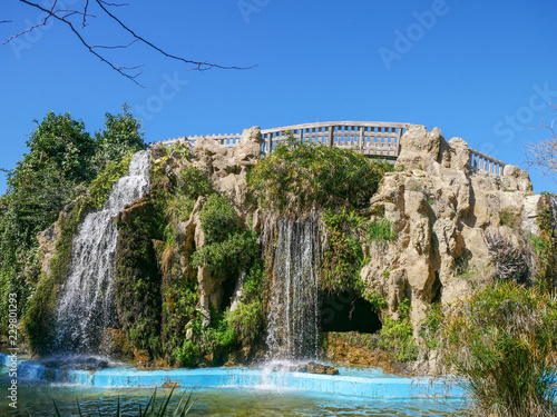 Artificial waterfall with a bridge over stone in the park Parque Genovés in Cádiz, Spain