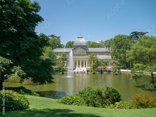 Palacio de Cristal - Glass Palace seen from across a pond in a public park in Parque de Retiro, Madrid, Spain, old historical building in a garden