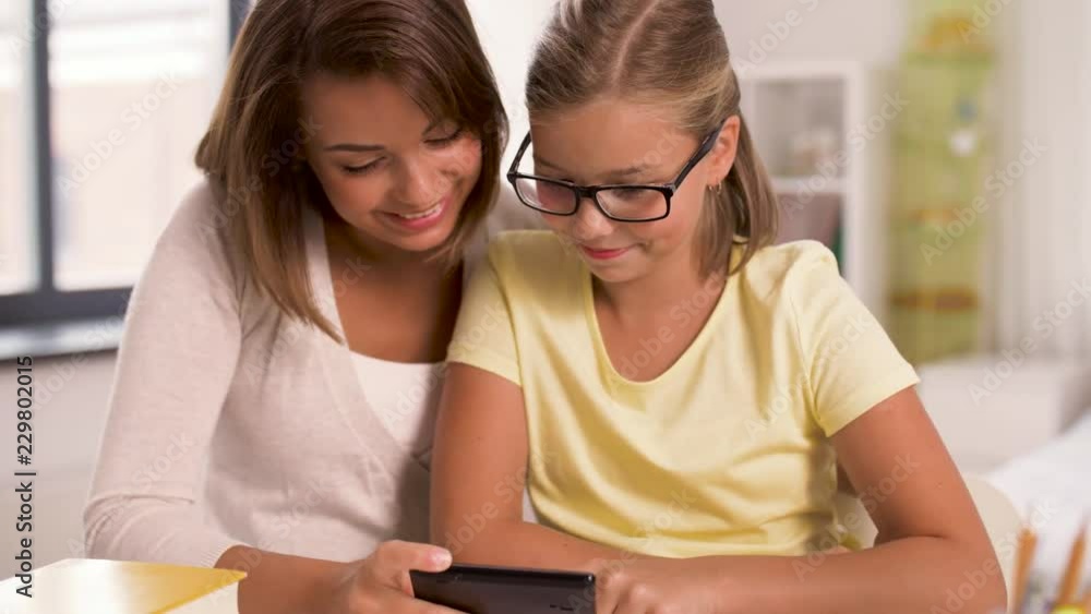 family, technology and people concept - happy mother and daughter with smartphone taking selfie at home family, technology and people concept - happy mother and daughter with smartphone taking selfie at home
