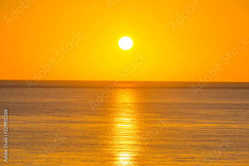Fototapeta Naklejka Na Ścianę i Meble -  Sunset over sea below a yellow sun in a yellow sky at fall