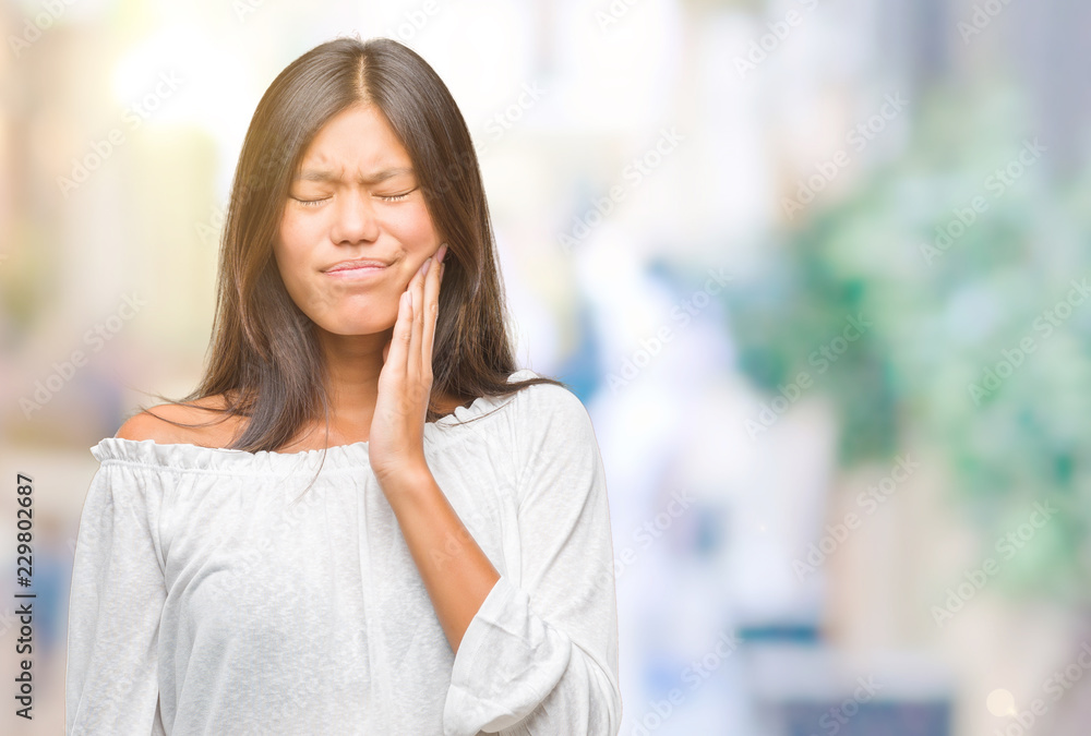 Young asian woman over isolated background touching mouth with hand with painful expression because of toothache or dental illness on teeth. Dentist concept.