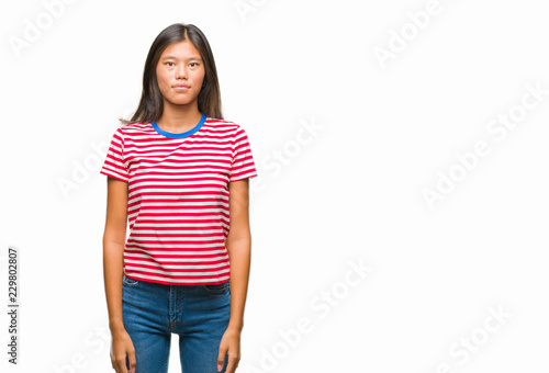 Young asian woman over isolated background with serious expression on face. Simple and natural looking at the camera.