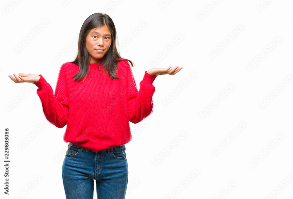 Young asian woman wearing winter sweater over isolated background clueless and confused expression with arms and hands raised. Doubt concept. Young asian woman wearing winter sweater over isolated background clueless and confused expression with arms and hands raised. Doubt concept.