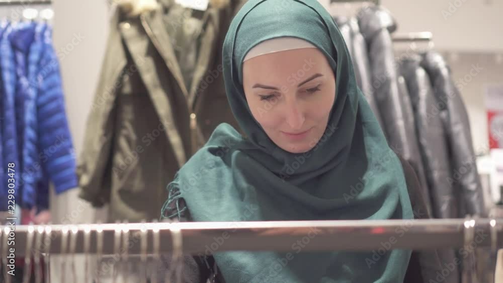 Pretty muslim woman in hijab and with a backpack on shopping in the store,close up Pretty muslim woman in hijab and with a backpack on shopping in the store,close up