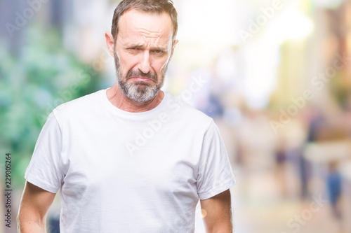 Middle age hoary senior man wearing white t-shirt over isolated background depressed and worry for distress, crying angry and afraid. Sad expression.