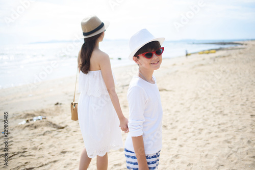  happy family mother with boy walks holding hand on the beach ,white sand beach  ,look happy in the summer
