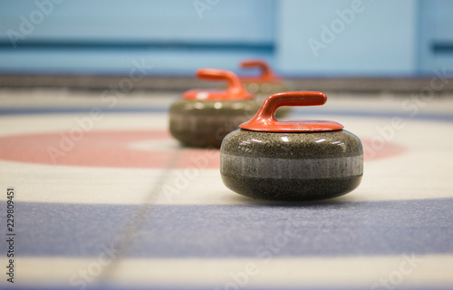 two granite curling rocks on the ice