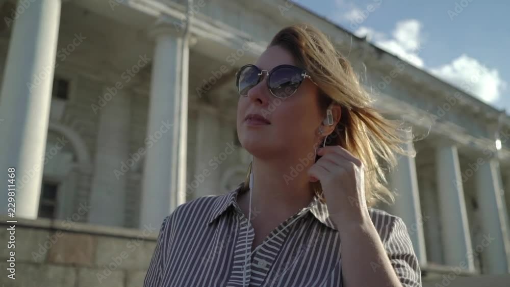 Young blonde woman smiling and posing in a city slowmotion at the summer evening Young blonde woman smiling and posing in a city slowmotion at the summer evening