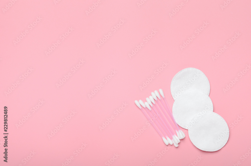 Cotton buds and cotton pads on a pink background. Hygiene supplies, beauty tools. Top view, copy space, flat lay
