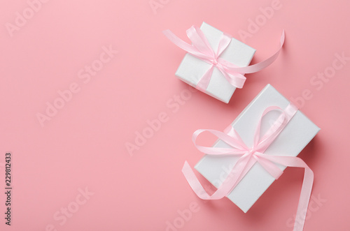 White gift box on a pink background with a pink ribbon. A birthday present, women's day or Christmas. Top view, save space, flat lay © mellisandra