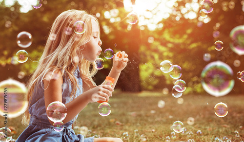 Valokuva Portrait of a cheerful girl blowing soap bubbles