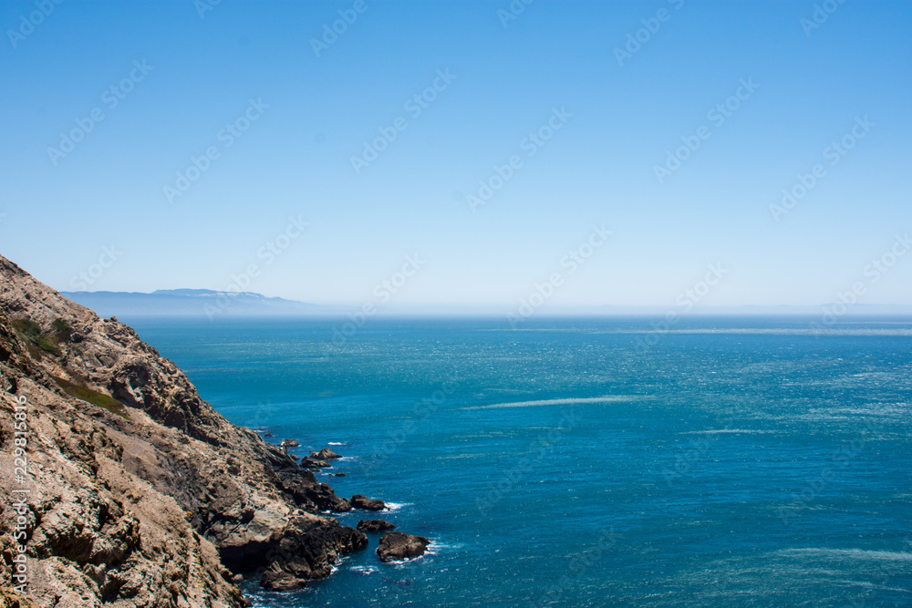 Oceanside cliffs at Point Reyes National Seashore in Marin County, California. Bright blue color of the Pacific Ocean, on a sunny day, with extra copyspace