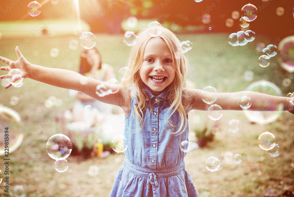 Cheerful little girl enjoying bubble blowing - obrazy, fototapety, plakaty 
