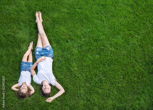 Conceptual portrait of a mother relaxing with daughter on a fresh, green lawn