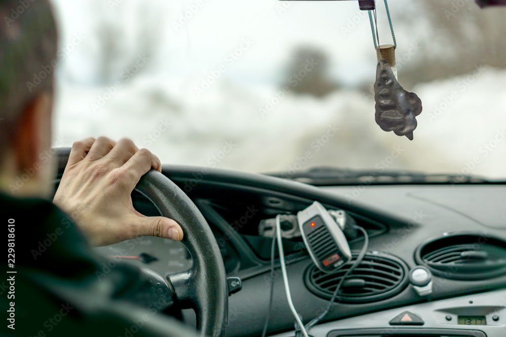 Close-up of a driver's hand on a cold winter day. Through the window there were large driven snow on both sides of the road. Winter season, road. Snow catastrophes, risky dangers during driving. Close-up of a driver's hand on a cold winter day. Through the window there were large driven snow on both sides of the road. Winter season, road. Snow catastrophes, risky dangers during driving.