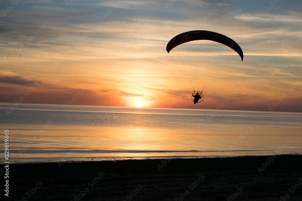 Paraglider over the sea at sunset.