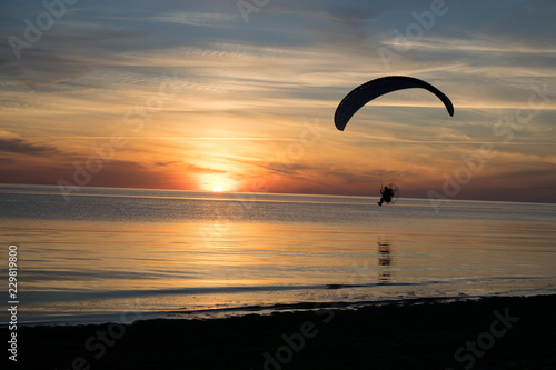 Paraglider over the sea at sunset.