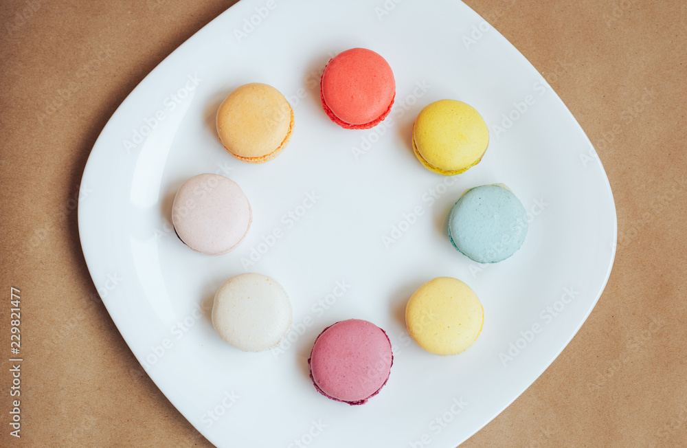 multi-colored macaroons on a white plate craft background multi-colored macaroons on a white plate craft background