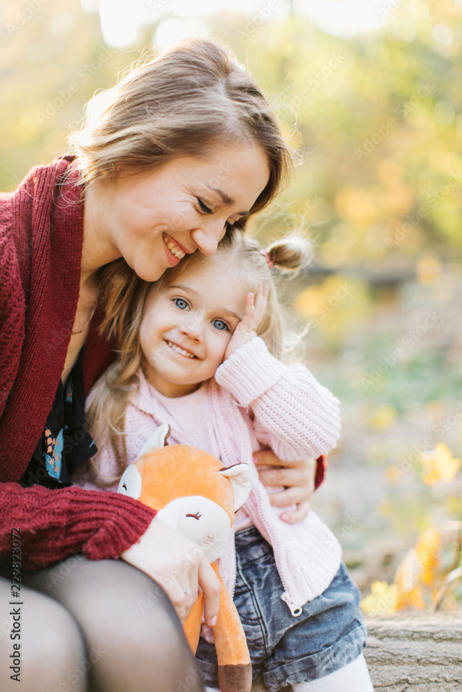 young mother and daughter are walking in the park in the golden autumn young mother and daughter are walking in the park in the golden autumn
